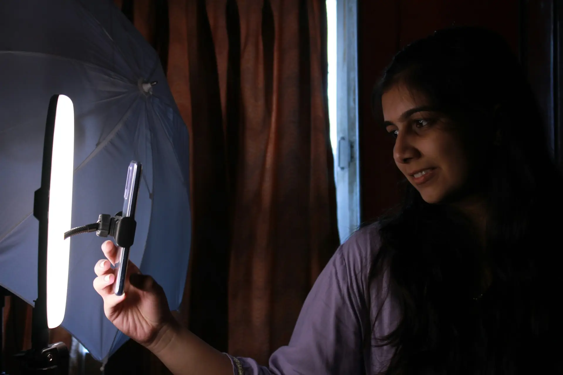 Woman holding phone in front of a ring light