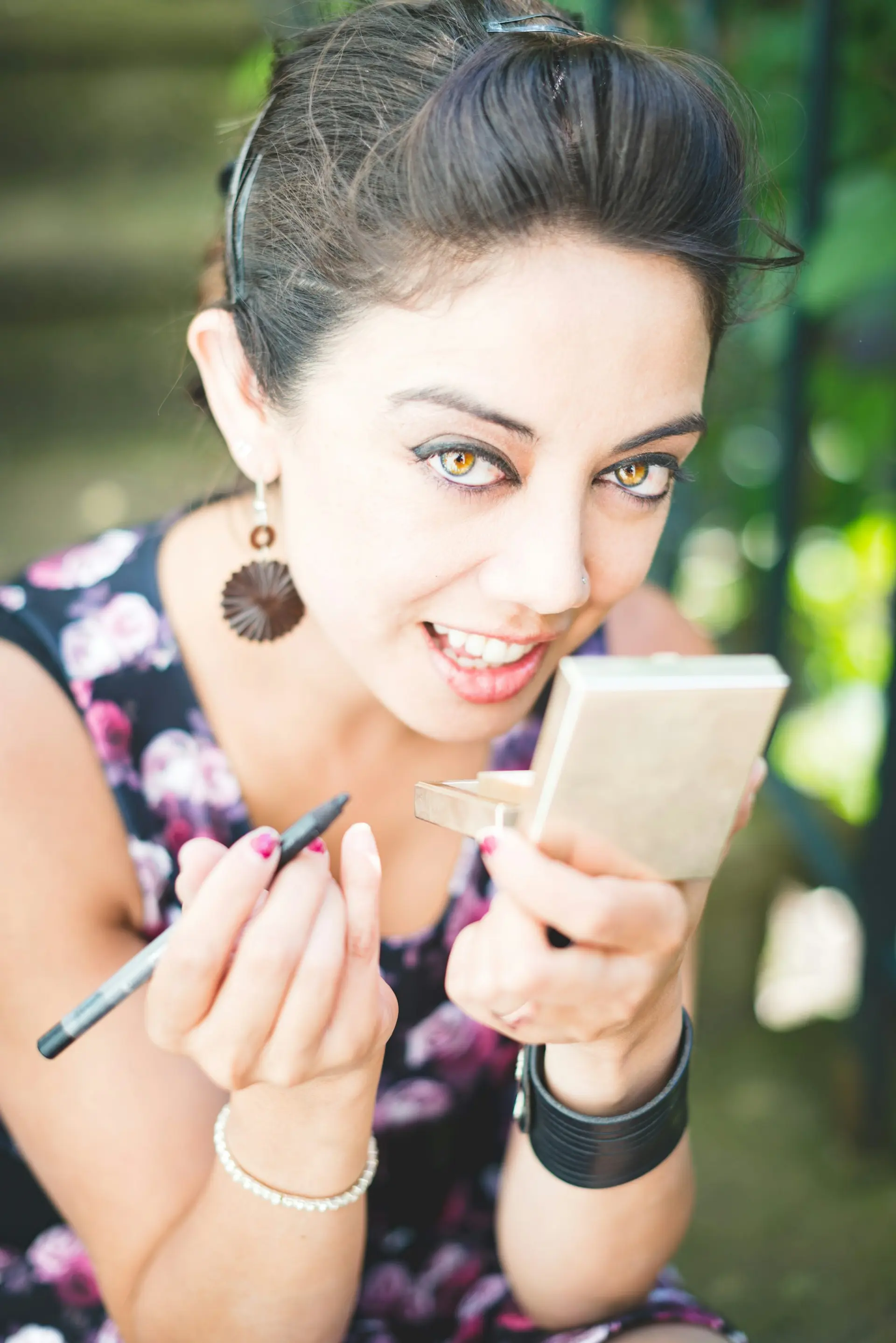 Smiling woman with mirror and eyeliner